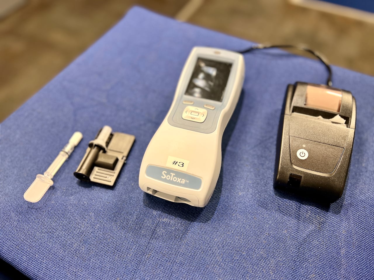 A grey and white device sit on a table with a blue cloth.