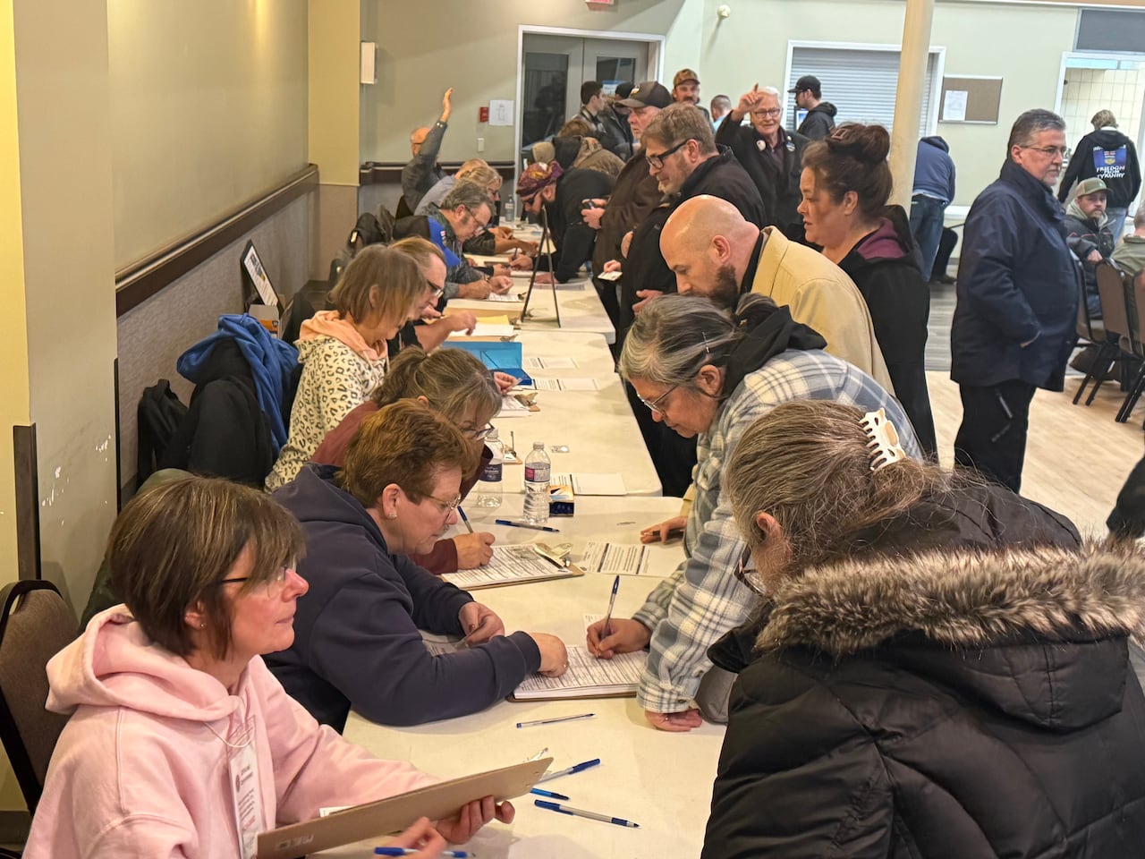People lining up near tables to sign some forms.