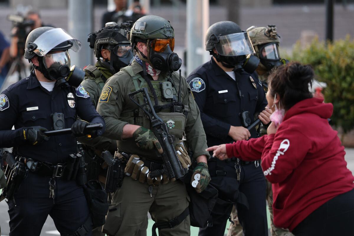 A protester gestures toward police and US CBP agents outside the US Citizenship and Immigration Services (USCIS) Santa Ana 
