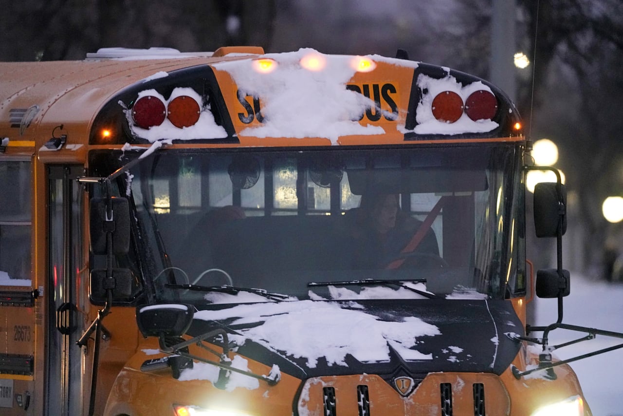 A school bus is covered in snow during a blizzard.