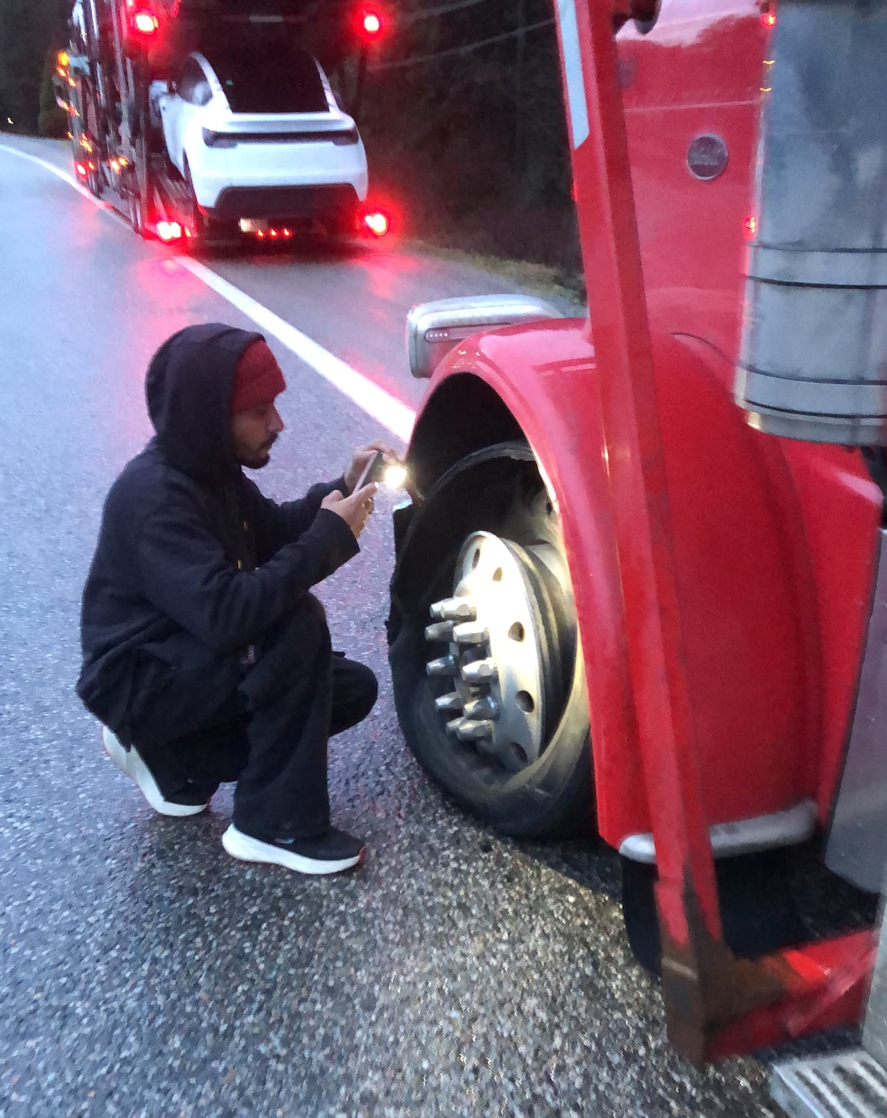 A person photographs a blown tire on a truck
