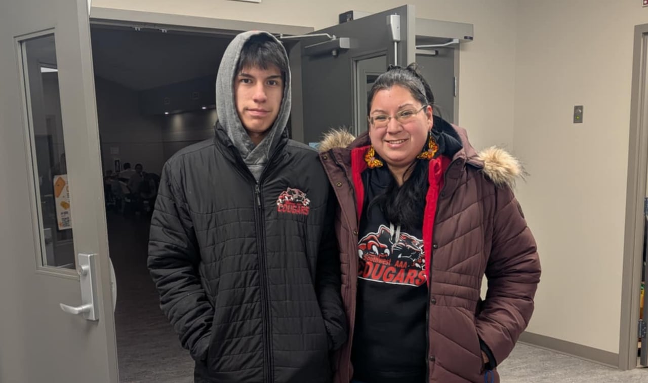 Two people in winter clothes stand in a community centre hallway.