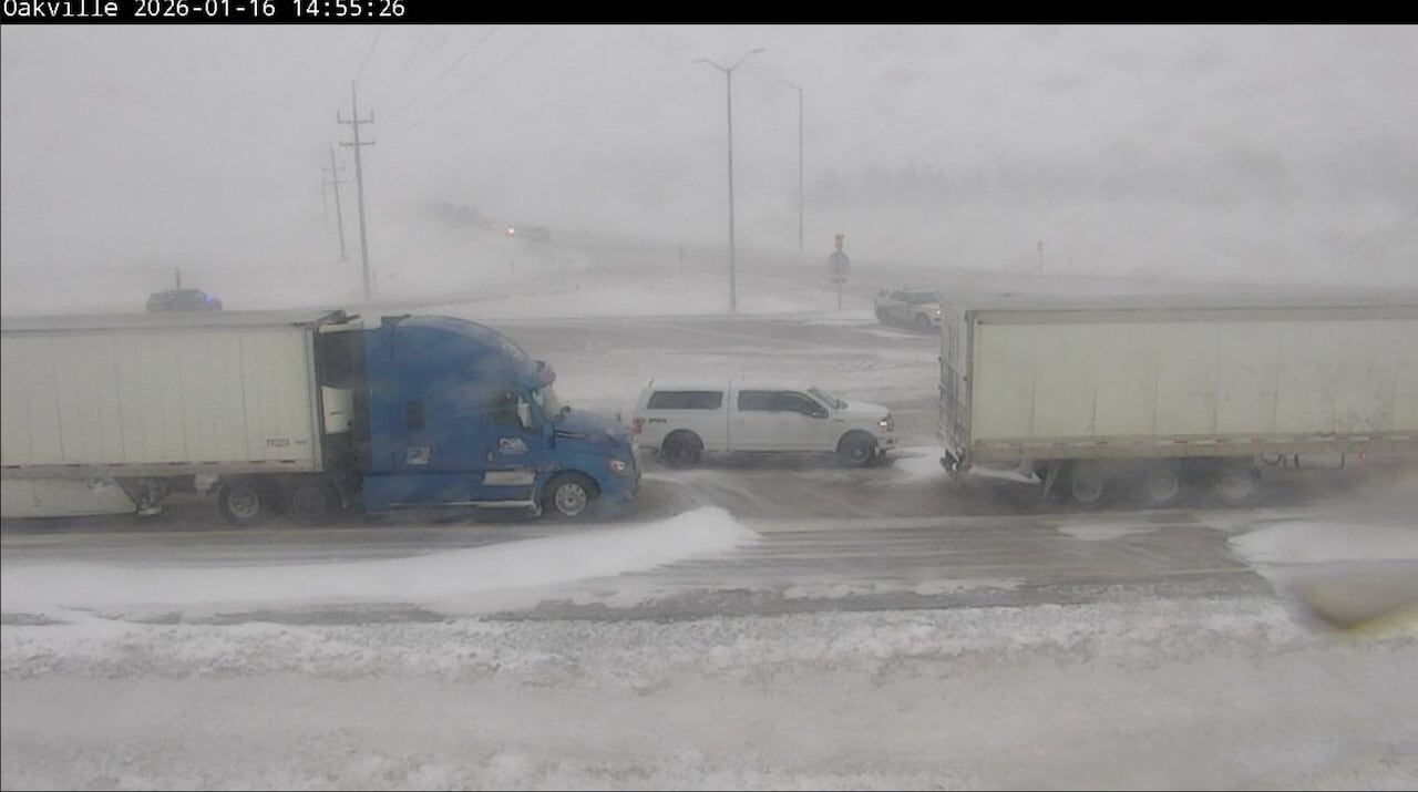 Two semis and another vehicle are stopped on an icy highway.
