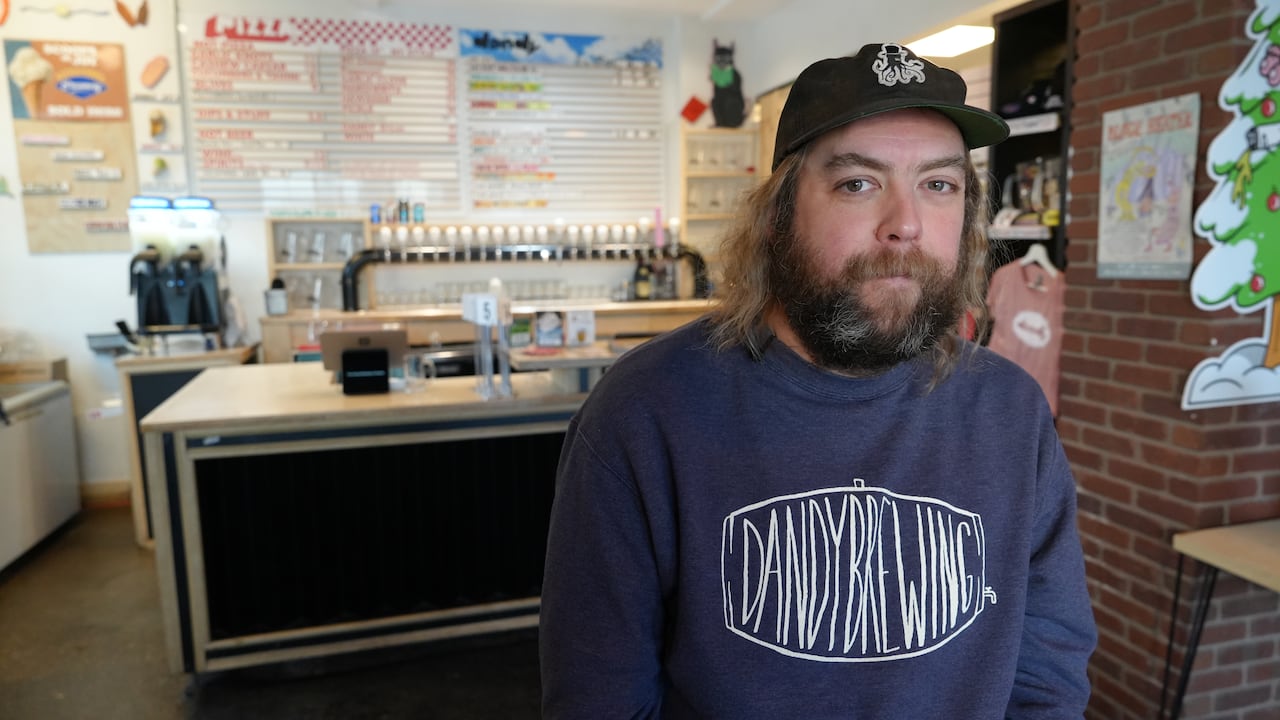 A man wearing a "Dandy Brewing" sweatshirt is pictured in the brewery's taproom.
