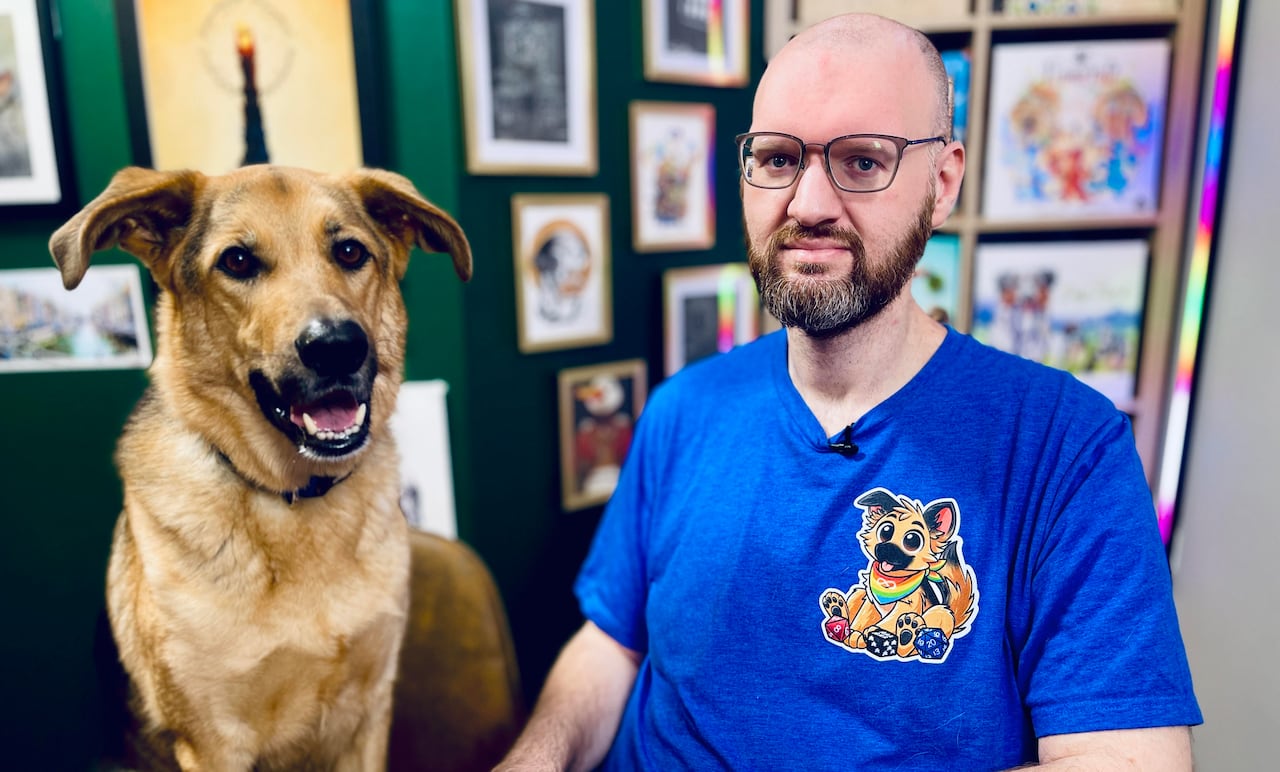 A man and a dog sit side by side, looking at the camera