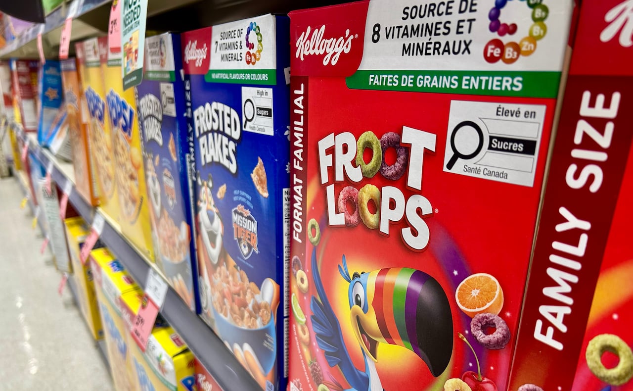 Cereal boxes on a grocery store shelf, including Fruit Loops and Frosted Flakes, that now carry the magnifying glass symbol to alert shoppers it's high in saturated fat, sodium and/or sugar.