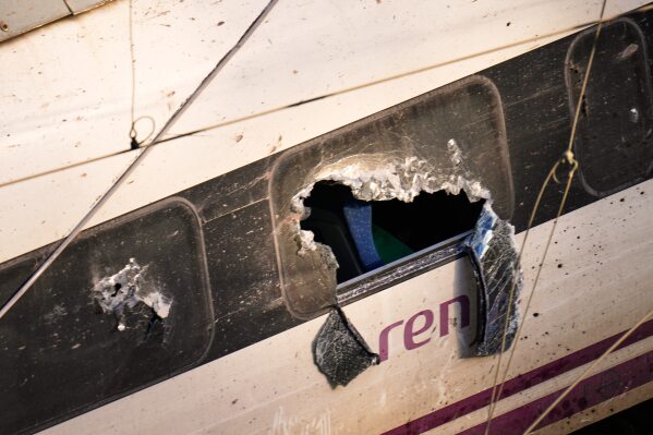 Broken windows of a crashed train are photographed at the site of a train collision in Adamuz, southern Spain, Monday, Jan. 19, 2026. (AP Photo/Manu Fernandez)