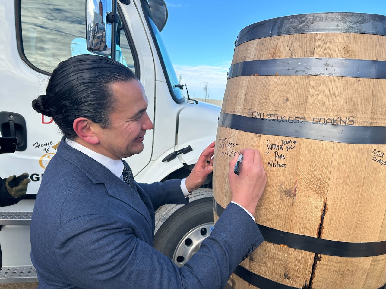 Manitoba Premier Wab Kinew signs barrels outside the Diageo plant where Crown Royal whisky is produced, in Gimli, Man., Jan. 13, 2026. Kinew is calling on Ontario Premier Doug Ford to cancel a planned boycott of the whisky. 