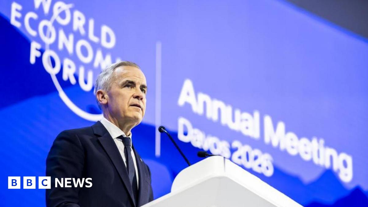 Donald Trump and Keir Starmer sit in a formal drawing room setting  on arm chairs with US and UK  flags behind them. Both have serious expressions and are looking out and not at each other.