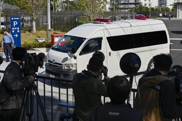 Journalists crowd as a vehicle which is belived to be carrying Tetsuya Yamagami, the accused killer of former Japanese Prime Minister Shinzo Abe, leaves a detention center in Osaka, western Japan for a trial Tuesday, Oct. 28, 2025. (Kyodo News via AP)