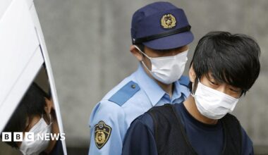 Tetsuya Yamagami, suspected of killing former Japanese Prime Minister Shinzo Abe, is escorted by a police officer as he is taken to prosecutors, at a police station in Nara in 2022.