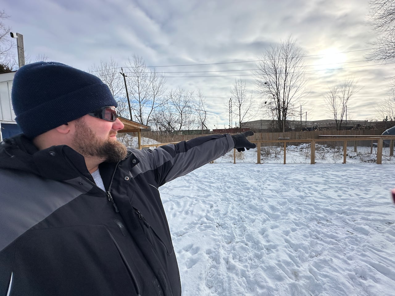 A man pointing to his backyard covered in snow.