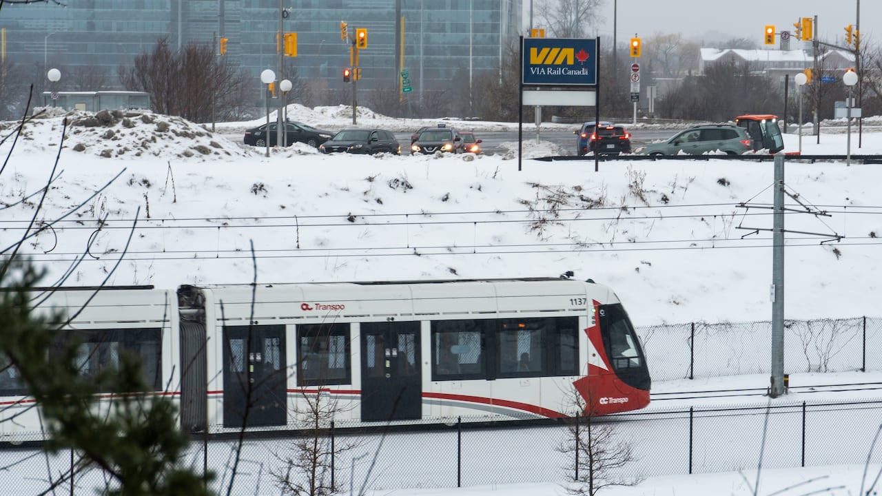 A light rail train passes a Via rail station.