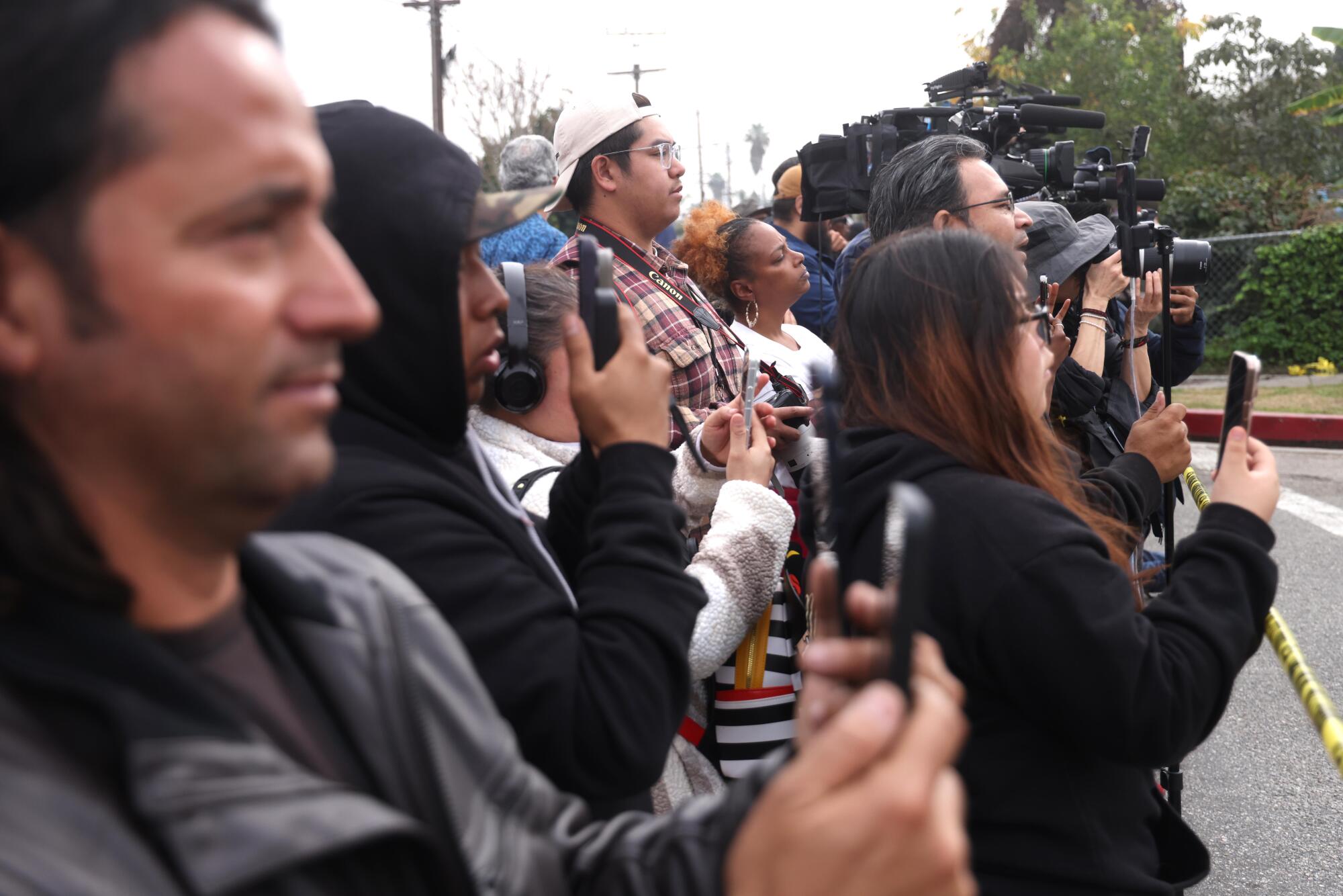 Spectators film and observe federal agents as they investigate a shooting in Willowbrook.