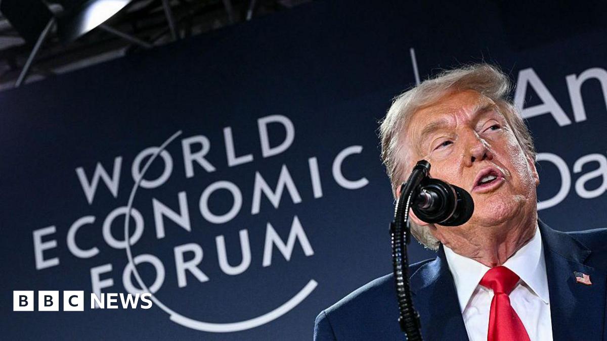 Close up shot of Donald Trump speaking into a microphone in front of a board with the words "World Economic Forum" on it.