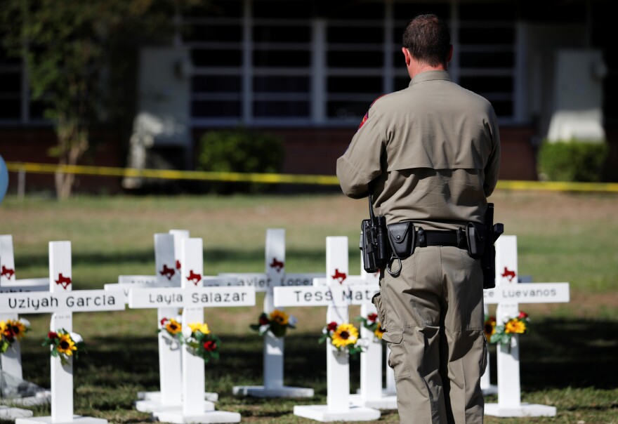 A Texas Department of Public Safety officer stands in front of crosses with the names of victims of a school shooting, at a memorial outside Robb Elementary school, two days after a gunman killed nineteen children and two adults in Uvalde, Texas, on May 26, 2022.
