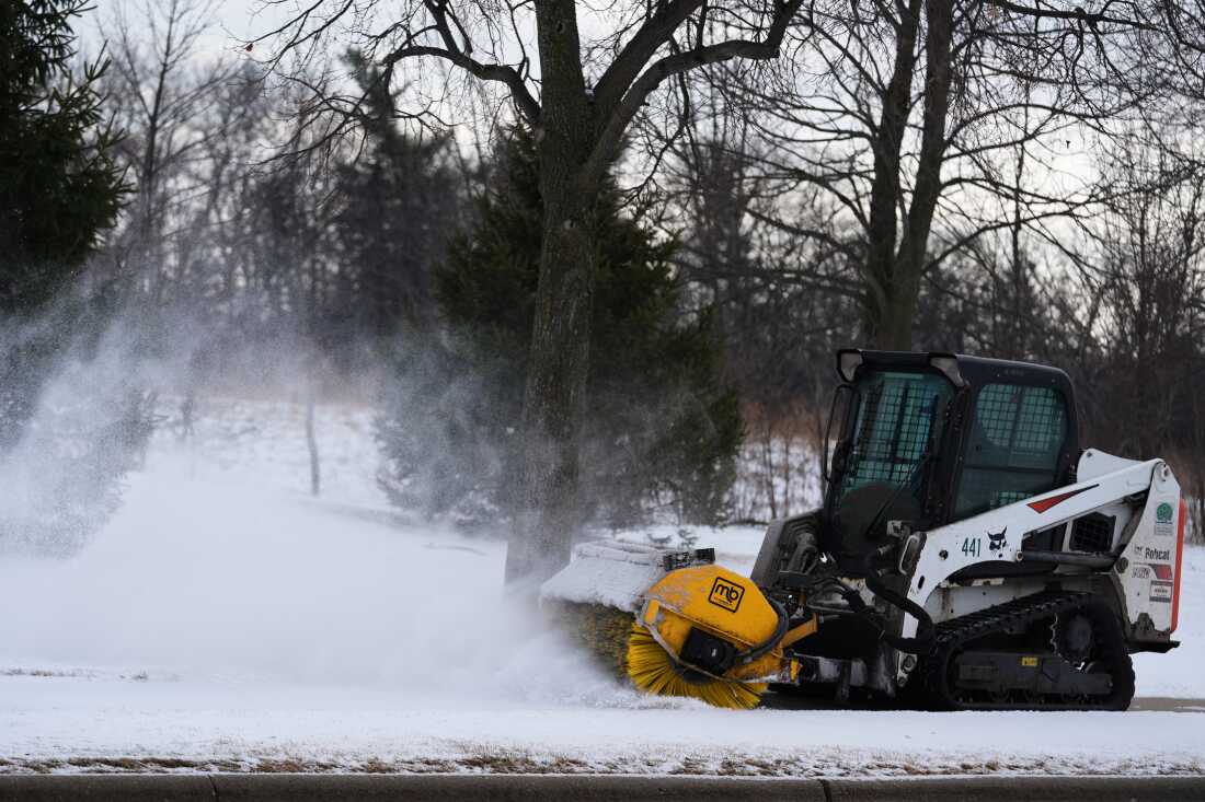 A plow clears snow from a snow-covered sidewalk during a cold day in Lake Forest, Ill., Wednesday, Jan. 21, 2026.