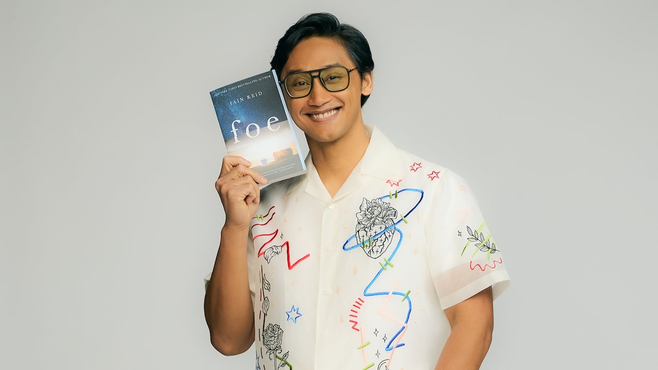 A man with glasses holding a book.