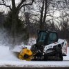 A plow clears snow from a snow-covered sidewalk during a cold day in Lake Forest, Ill., Wednesday, Jan. 21, 2026.