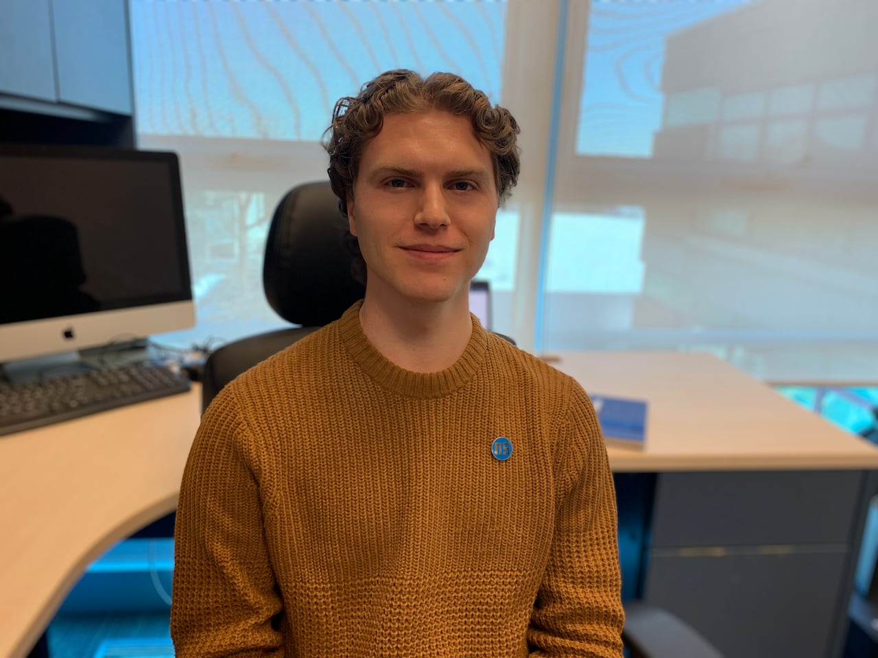 Portrait of a man with curly hair and a yellow sweater