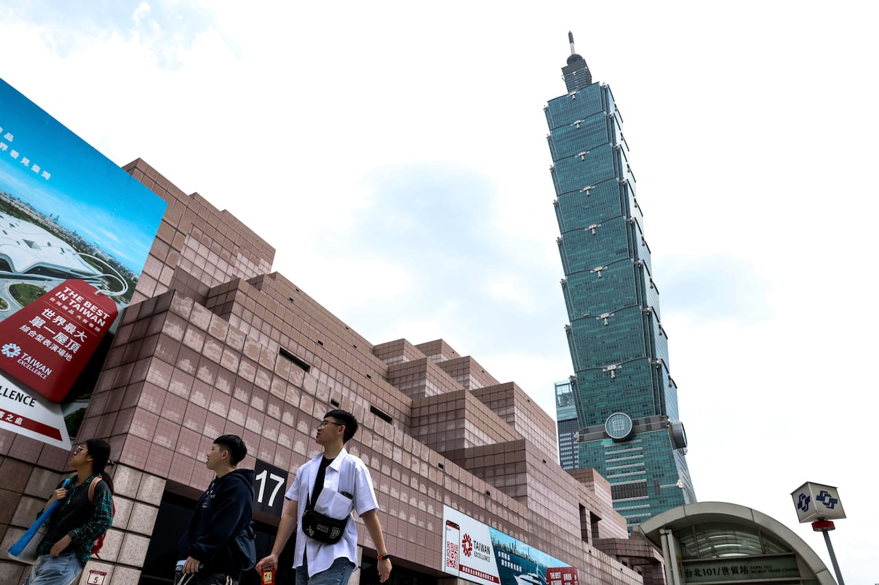 People walk on a street with a tall tower looming over them