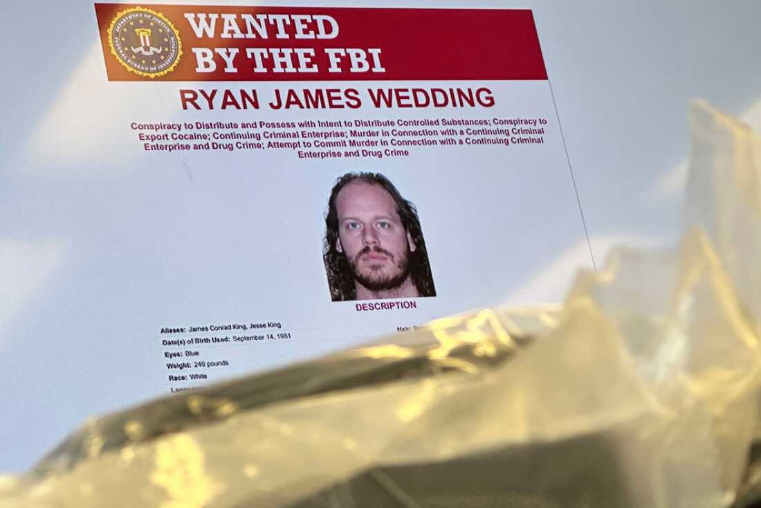 An image of former Canadian Olympic snowboarder Ryan Wedding, who was a fugitive and had been charged with allegedly running and participating in a transnational drug trafficking operation, is displayed on a video monitor along with bricks of cocaine, foreground, during an October 2024 news conference at the FBI offices in Los Angeles.