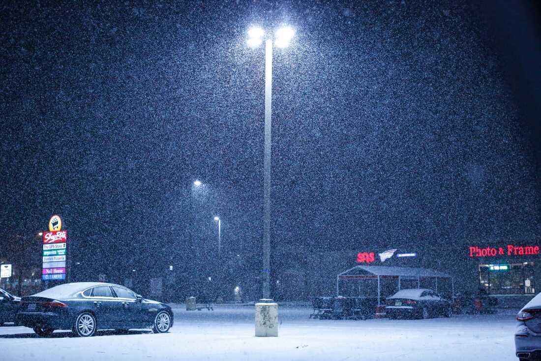 Snow falls on an empty parking lot outside a supermarket in December in Northvale, N.J.