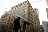 Pedestrians cross street during light rain, on Friday, Jan. 23, 2026, in downtown Dallas....
