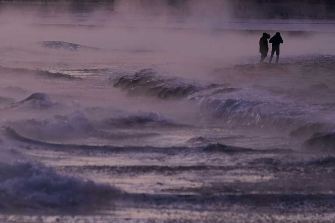 People walk on an ice covered beach along the shore of Lake Michigan, Friday, Jan. 23, 2026, in Chicago.