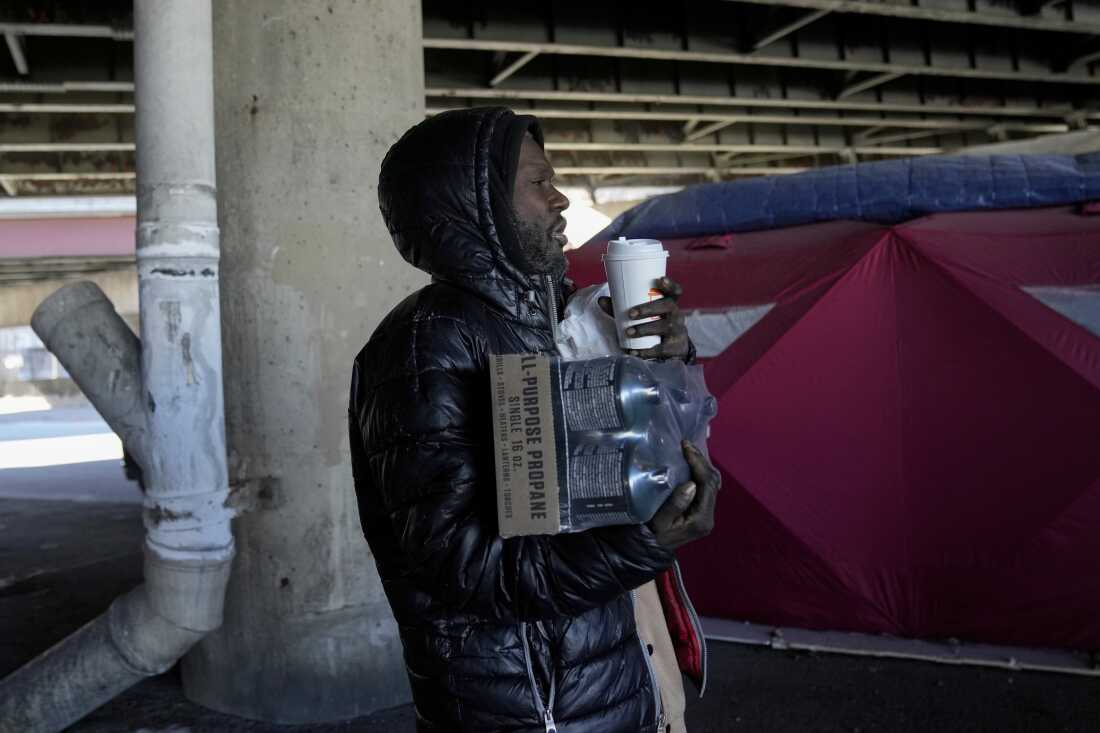 Unhoused individual Minyon McClure carries propane and other supplies from the Orange Tent Project nonprofit during dangerously cold temperatures Friday, Jan. 23, 2026, in Chicago. 
