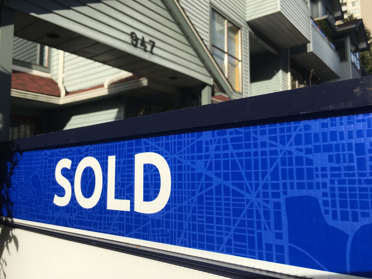 A sign reading 'sold' outside an apartment block.