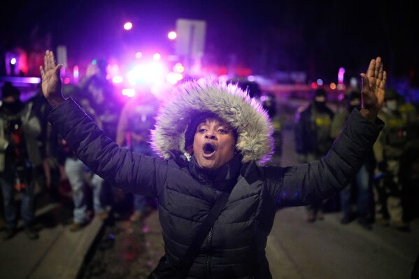 A protester yells in front of law enforcement after a shooting on Wednesday, Jan. 14, 2026, in Minneapolis. (AP Photo/John Locher)