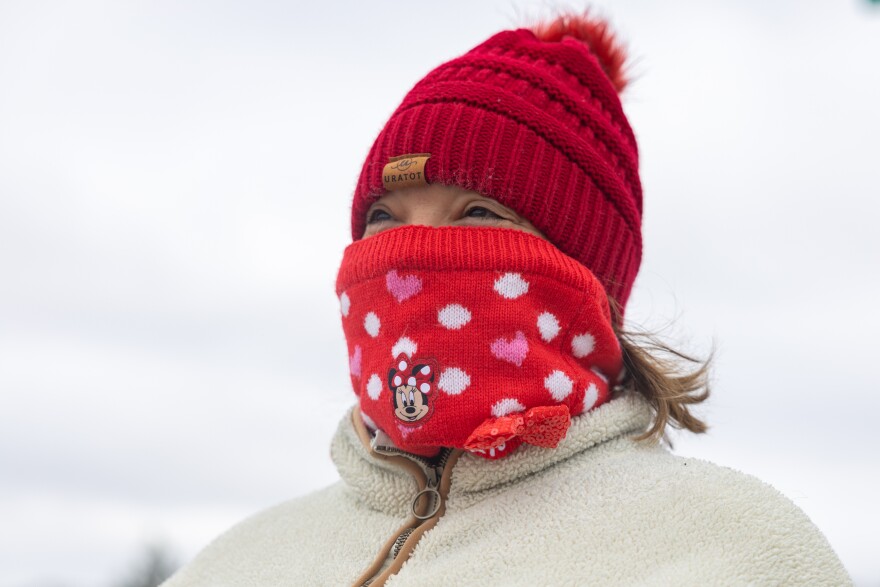 A woman's face is shown with most of her face covered in a Mickey Mouse scarf and a red hat.