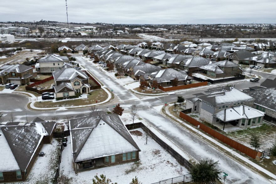 Houses and streets are seen from above covered in ice. 