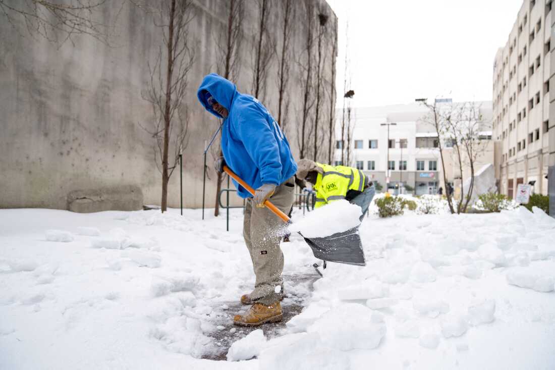 Memphis residents shovel snow from a sidewalk in downtown Memphis, Tenn., on Sunday.