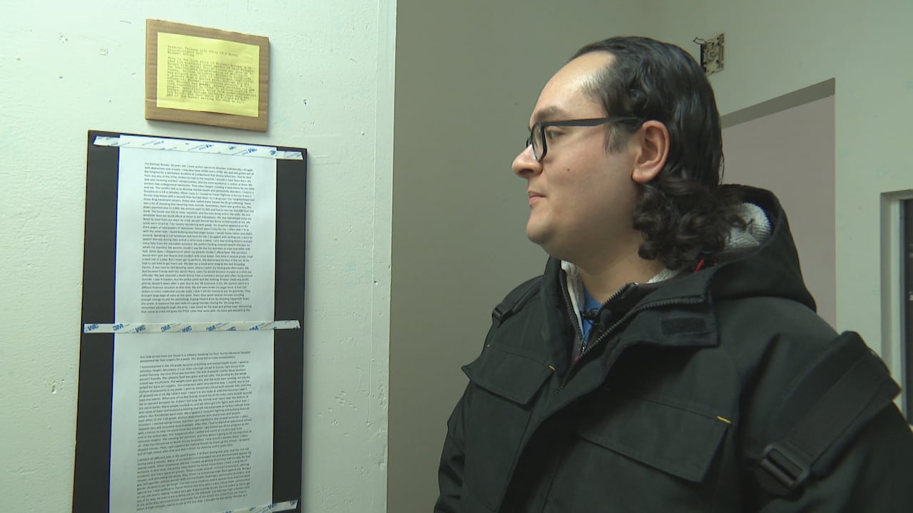 a person wearing glasses looks at a few printed sheets of text, mounted to the wall