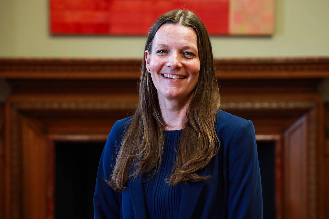A woman dressed in blue is pictured in front of a fire place.
