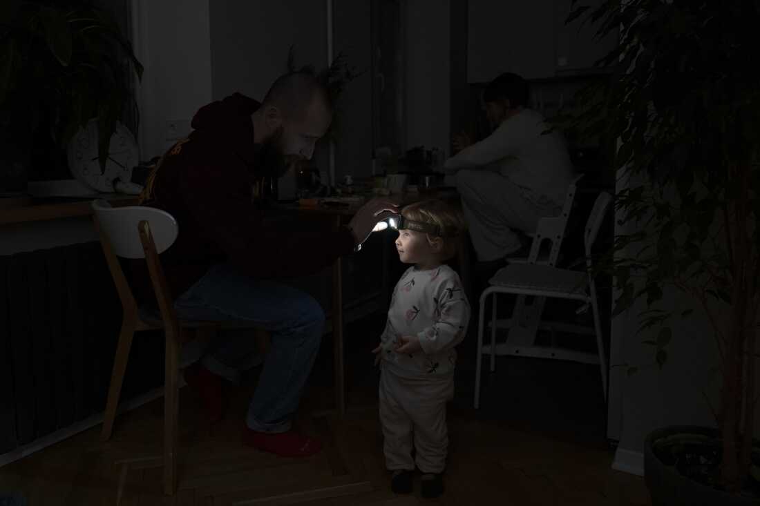 Local resident Stas helps his two-year-old daughter use a headlight