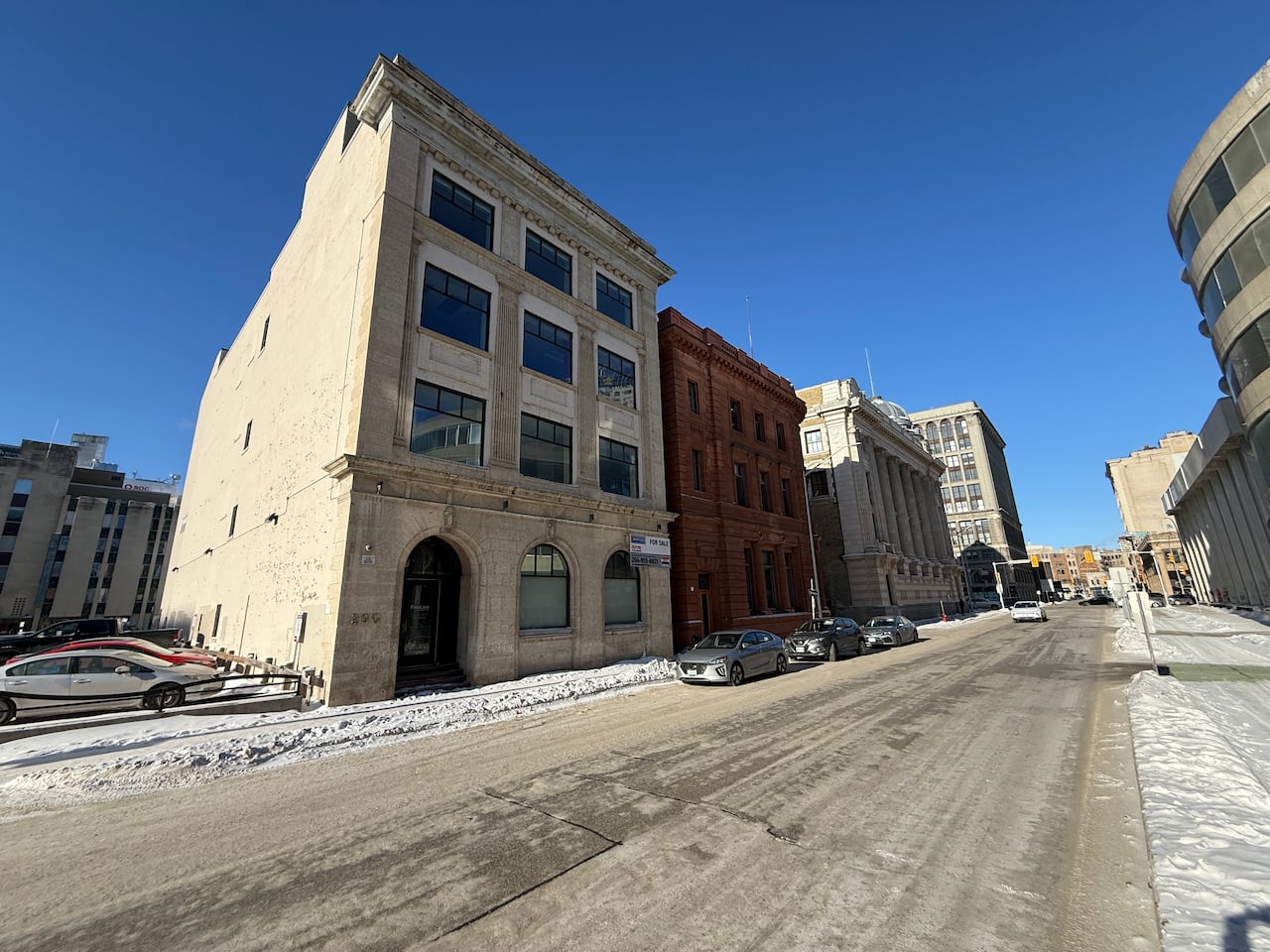 A white-brick building with a for-sale sign.