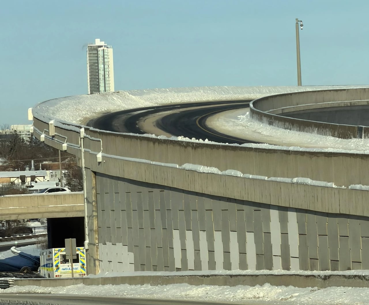 A photo of a highway ramp with snow accumulated on the shoulder.
