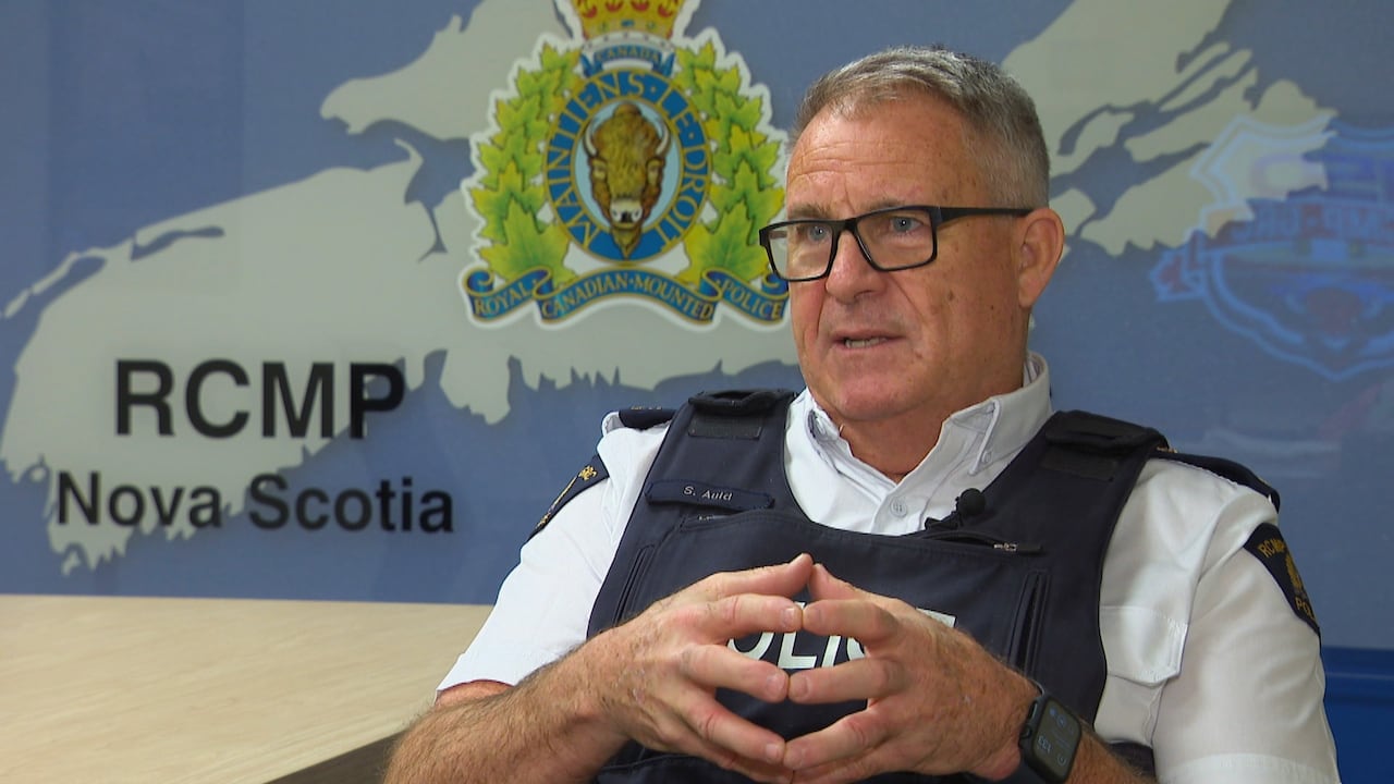 A man sits at a table wearing a police vest.