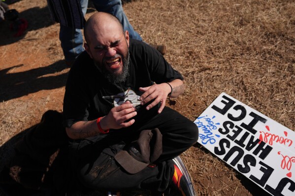 A protester reacts to the effects of pepper spray launched by Texas troopers to disperse protesters outside the South Texas Family Residential Center detention facility where Liam Ramos and his father are being detained in Dilley, Texas, Wednesday, Jan. 28, 2026. (AP Photo/Eric Gay)