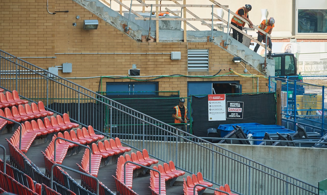 Construction workers are shown working in a stadium.