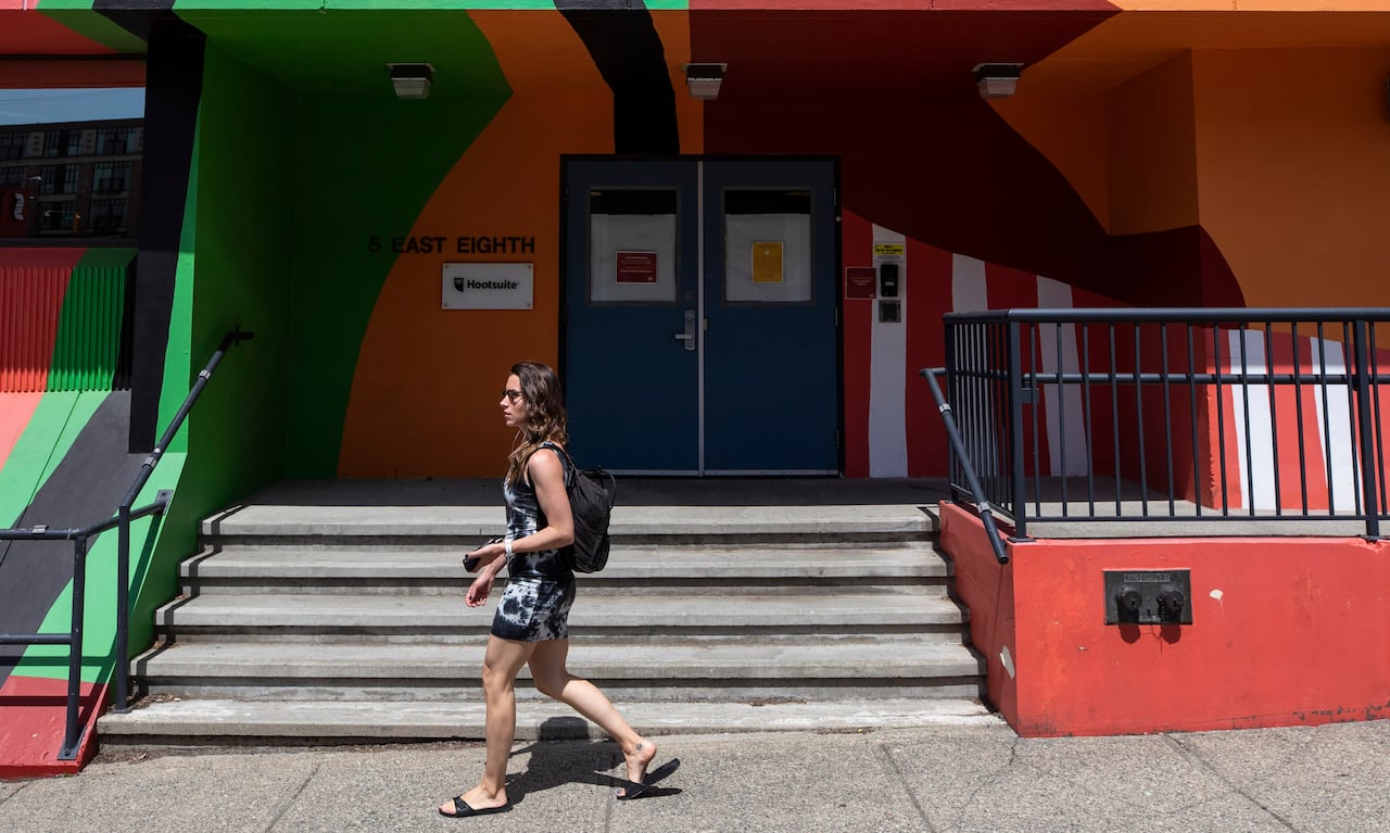 A woman walks past a colourful building on a sunny day.