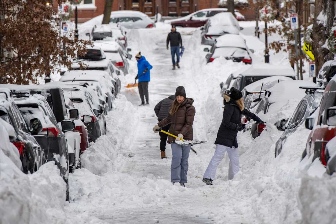 People shovel snow along a residential street in in Boston on Jan. 26, 2026.