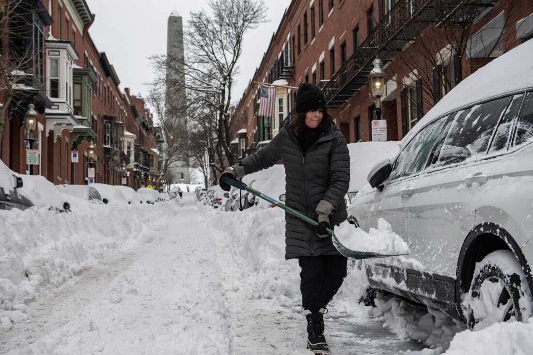 A woman digs out her car from the snow along a residential street in Boston on Jan. 26, 2026. 