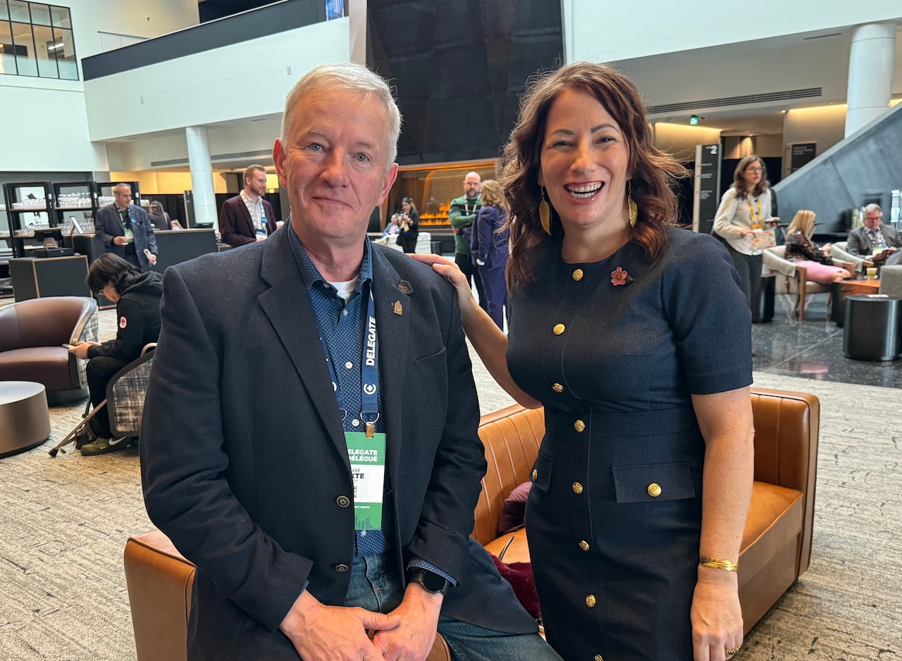 Two people stand and look at the camera.