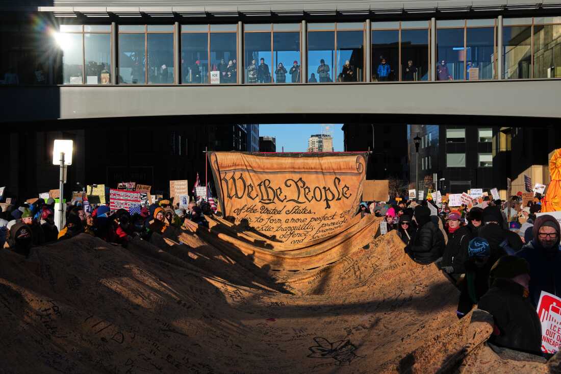 People hold a giant canvas depicting the opening words "We the People" from the U.S. constitution on Friday in Minneapolis.
