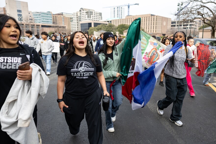 Students walk on a street holding signs and protesting.