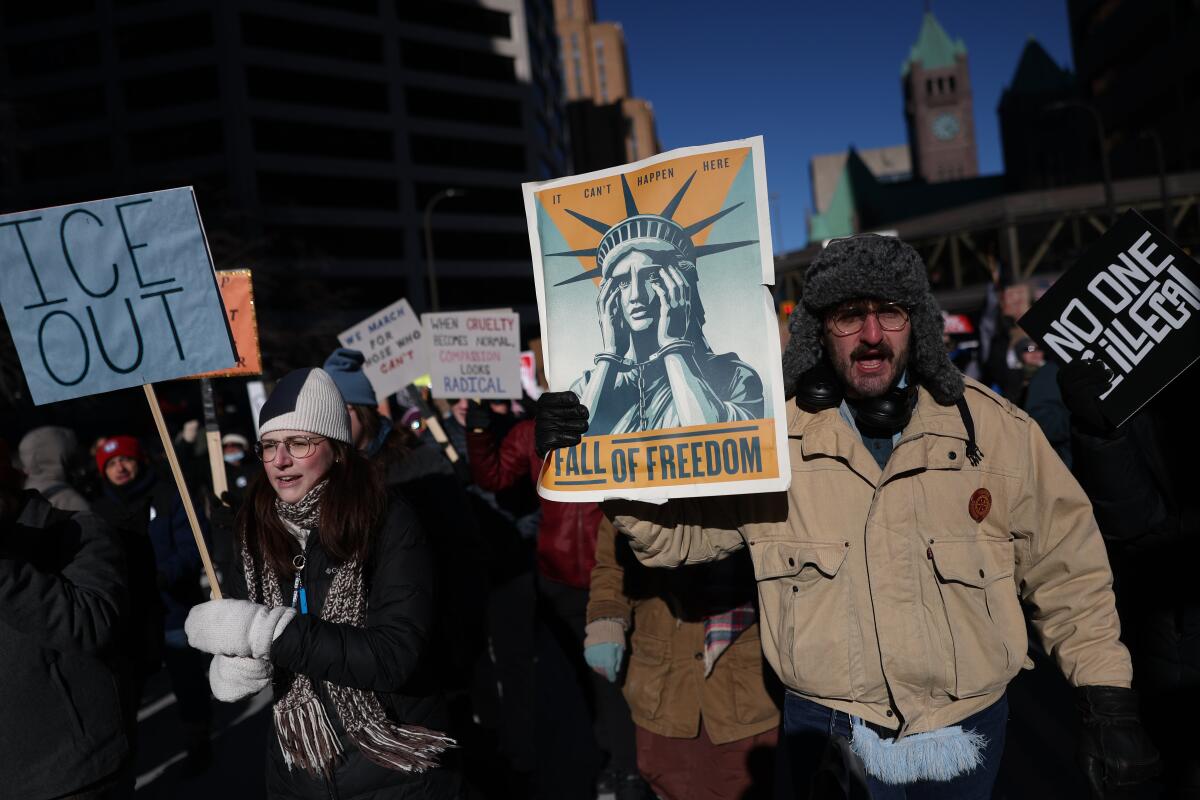 Protesters holding anti-ICE signs march.